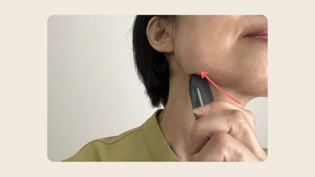 ヒートジュエルをあご下から耳の下へ滑らせる。矢印は動かす向き